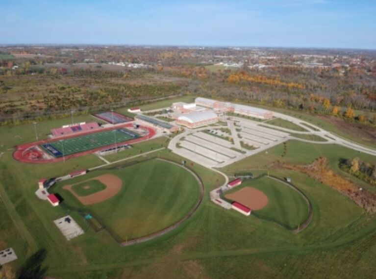 Aerial view of school building, baseball fields, and football field
